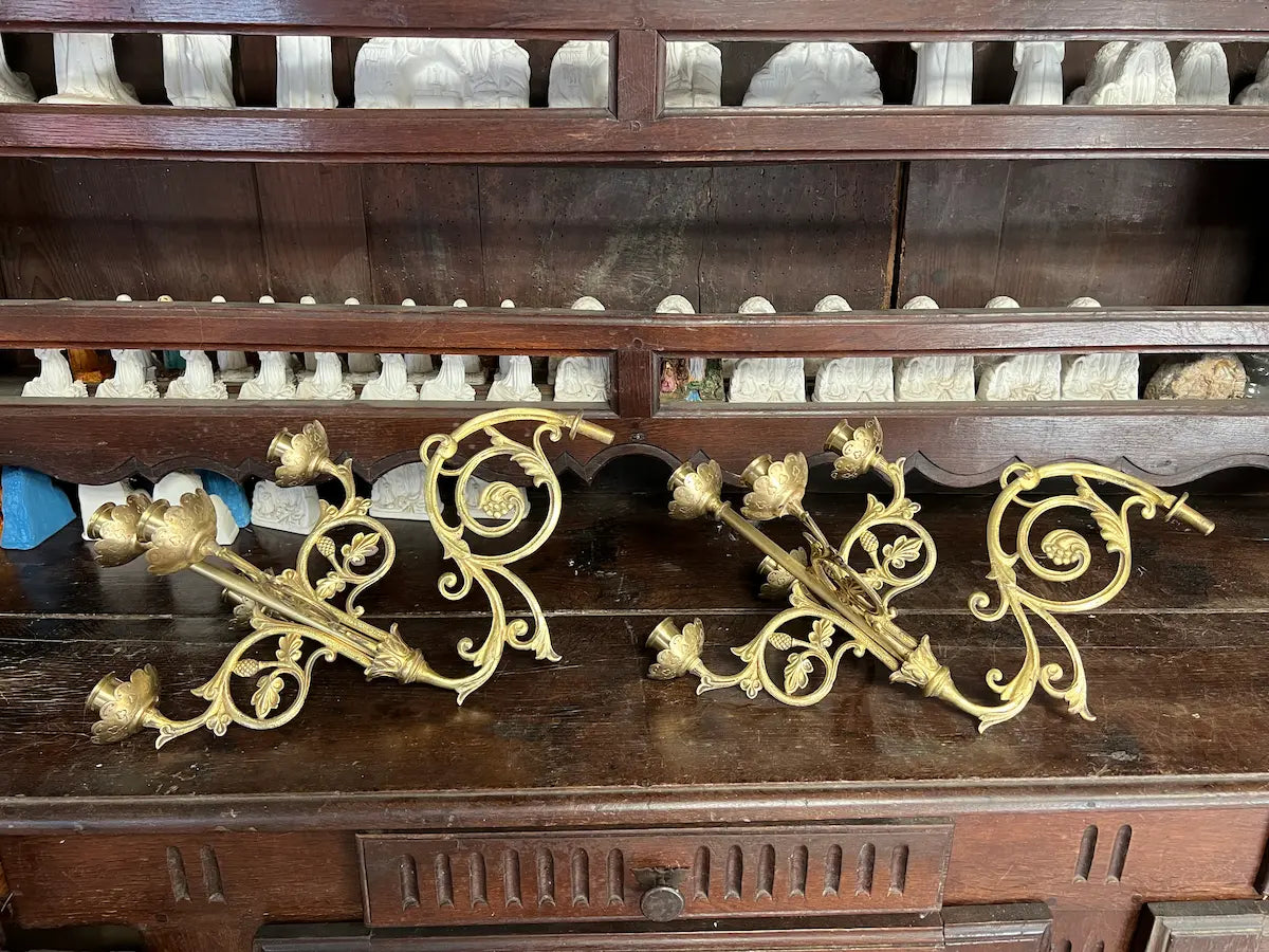 Pair of antique gilded bronze wall candelabra with five lights and ornate floral scrollwork, perfect for church or decorative use.
/
Paire d’appliques murales anciennes en bronze doré à cinq bougeoirs et volutes florales, idéales pour église ou décoration.