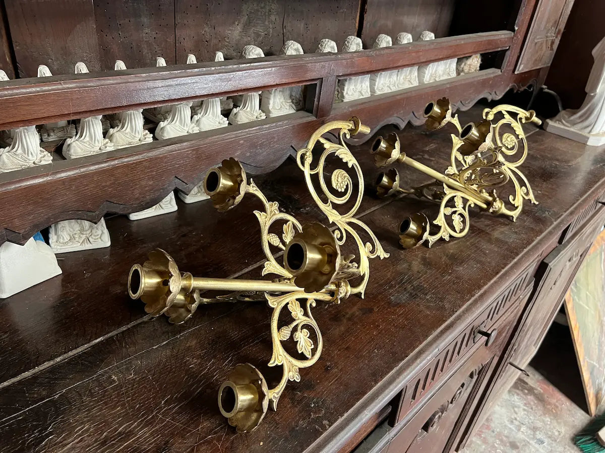 Pair of antique gilded bronze wall candelabra with five lights and ornate floral scrollwork, perfect for church or decorative use.
/
Paire d’appliques murales anciennes en bronze doré à cinq bougeoirs et volutes florales, idéales pour église ou décoration.