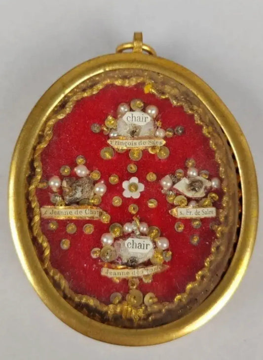 Antique oval reliquary containing relics of St. Francis de Sales and St. Jane de Chantal on red velvet background.
/
Reliquaire ovale ancien contenant des reliques de saint François de Sales et sainte Jeanne de Chantal sur fond en velours rouge.