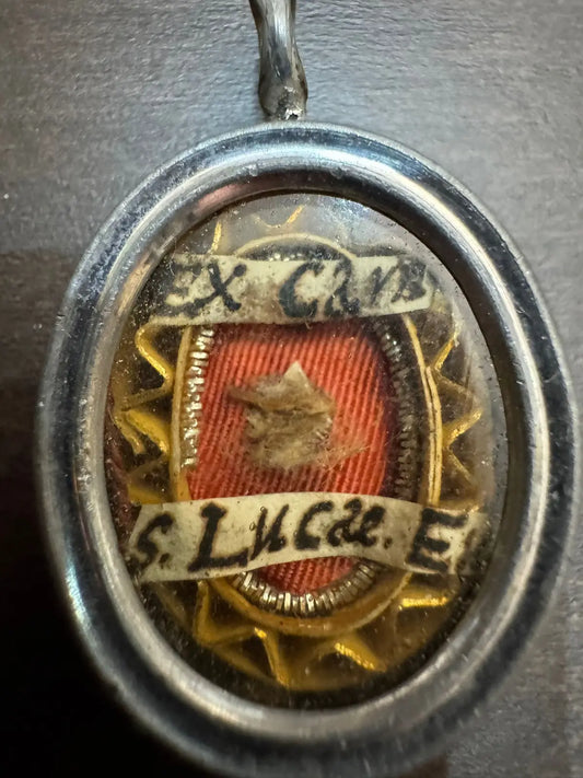 Relic of Saint Luke the Evangelist ex carne in oval silvered reliquary with flat glass front and certificate.
/
Relique de Saint Luc Évangéliste ex carne dans theca reliquaire ovale argentée avec façade en verre plat et certificat.