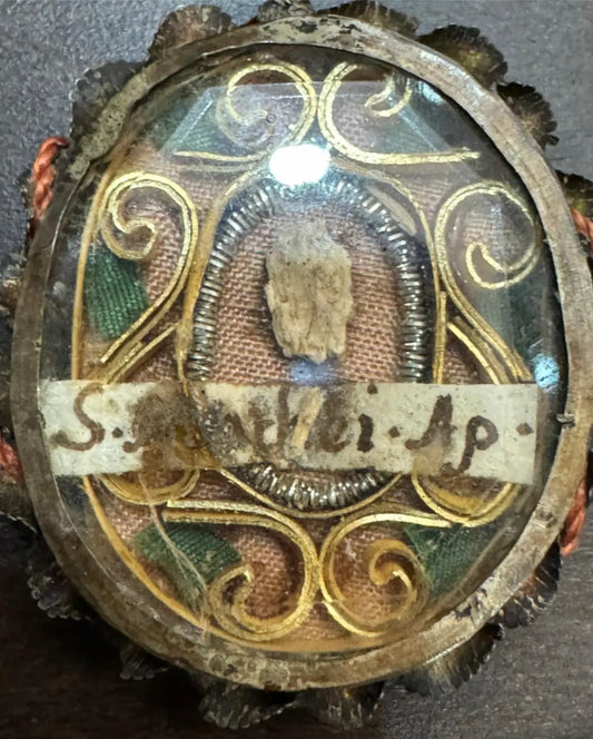 Relic of Saint Matthew the Apostle ex ossibus in ornate reliquary theca with flat glass front and certificate.

/ Relique de Saint Matthieu Apôtre ex ossibus dans une theca reliquaire ornée avec façade en verre plat et certificat.